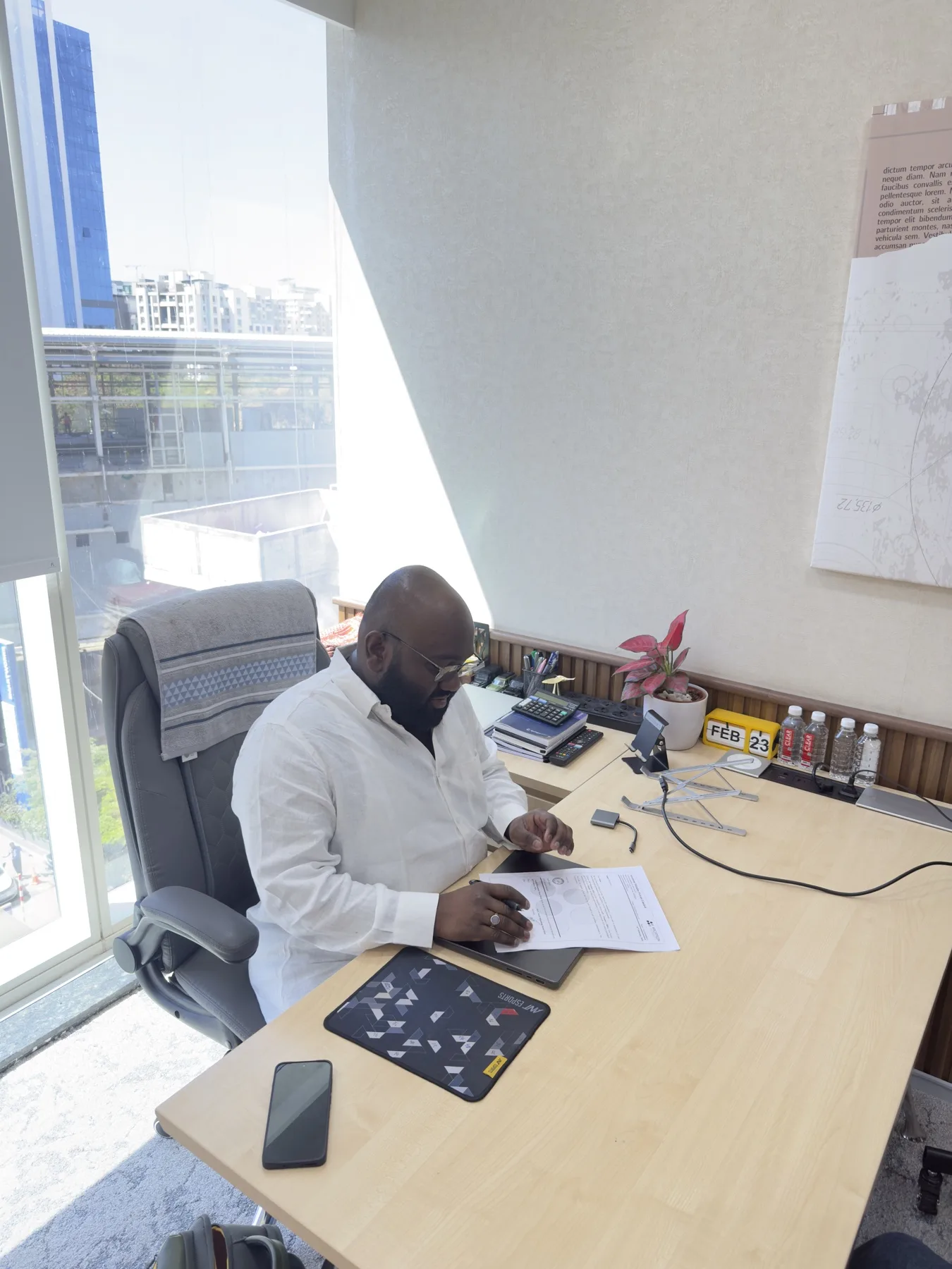 In a white kurta, reading at the desk